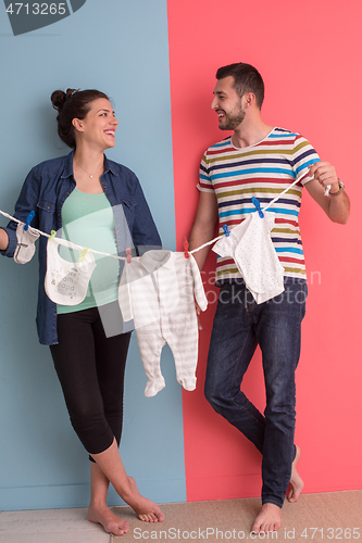 Image of young couple holding baby bodysuits