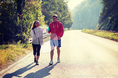 Image of young couple jogging along a country road