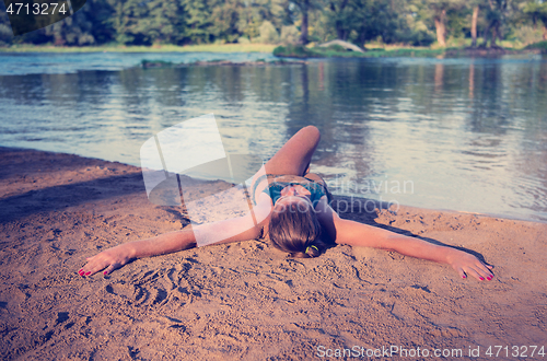 Image of girl in a green bikini relaxing on the riverbank