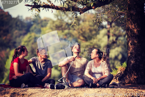 Image of friends smoking hookah on the river bank