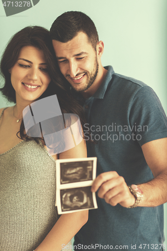 Image of couple looking ultrasound picture isolated on blue background