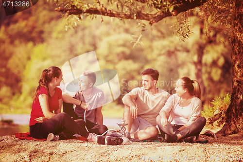 Image of friends smoking hookah on the river bank