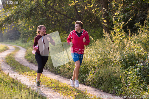 Image of young couple jogging along a country road