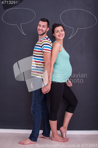 Image of pregnant couple writing on a black chalkboard