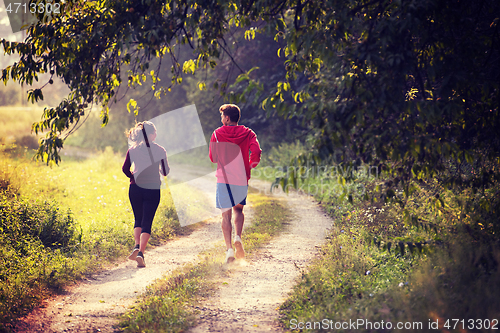 Image of young couple jogging along a country road