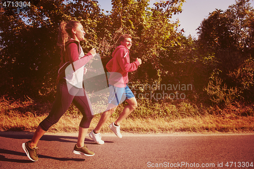 Image of young couple jogging along a country road