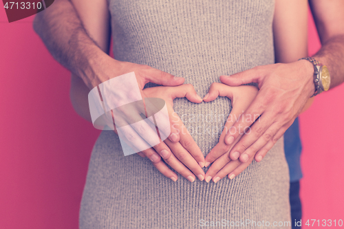 Image of pregnant  couple showing heart with their hands