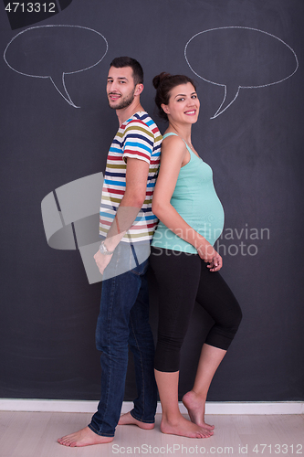 Image of pregnant couple writing on a black chalkboard