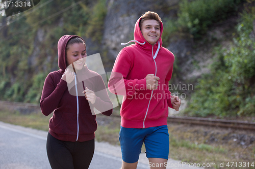 Image of young couple jogging along a country road