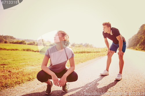 Image of young couple warming up and stretching on a country road