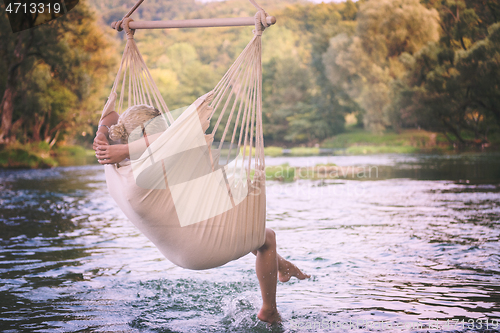 Image of blonde woman resting on hammock