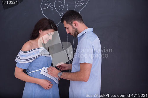 Image of pregnant couple drawing their imaginations on chalk board