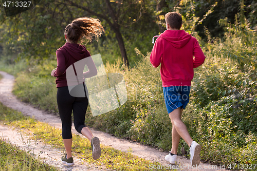 Image of young couple jogging along a country road