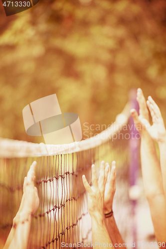 Image of group of young friends playing Beach volleyball