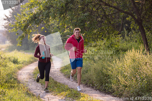 Image of young couple jogging along a country road