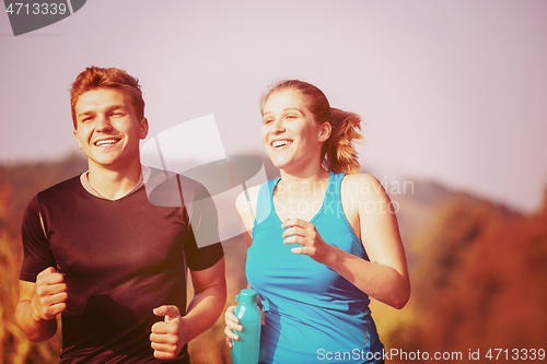Image of young couple jogging along a country road