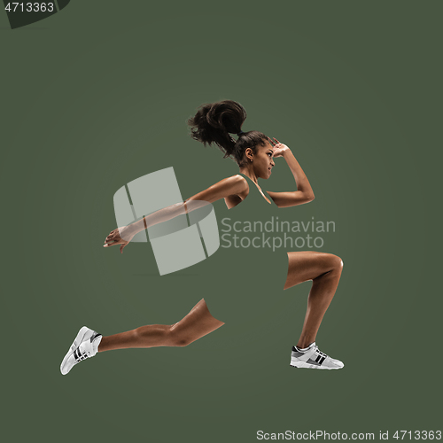 Image of Young african woman running or jogging isolated on green studio background.