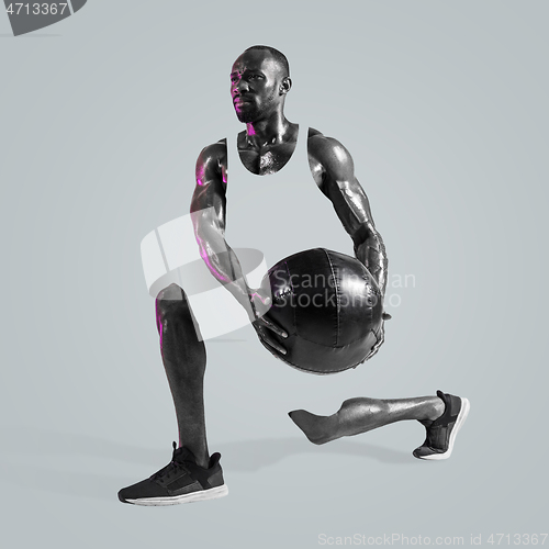 Image of Young african-american bodybuilder training over gray background