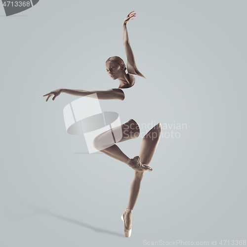 Image of Ballerina. Young graceful female ballet dancer dancing over grey studio. Beauty of classic ballet.