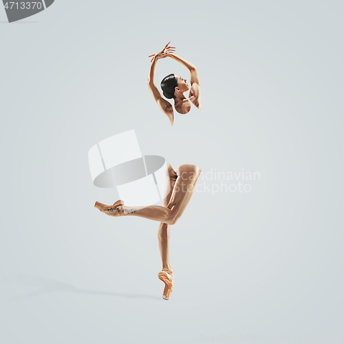 Image of Ballerina. Young graceful female ballet dancer dancing over grey studio. Beauty of classic ballet.