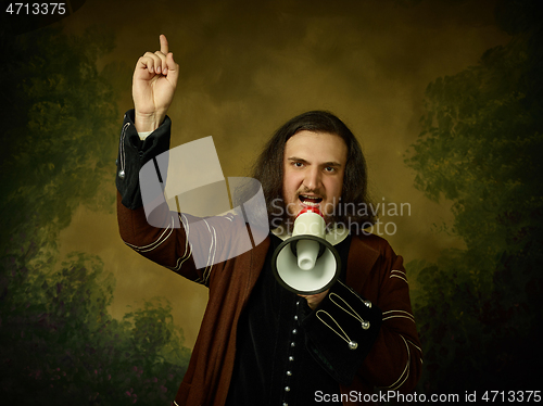 Image of Young man as a medieval knight on dark background