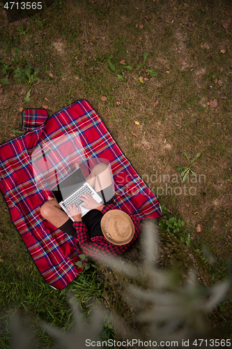 Image of top view of man using a laptop computer under the tree