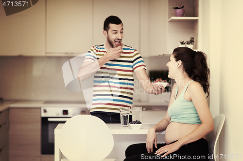 Image of couple eating fruit strawberries at kitchen