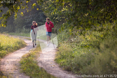 Image of young couple jogging along a country road