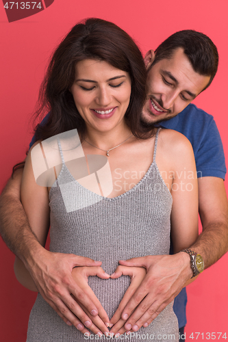 Image of pregnant  couple showing heart with their hands