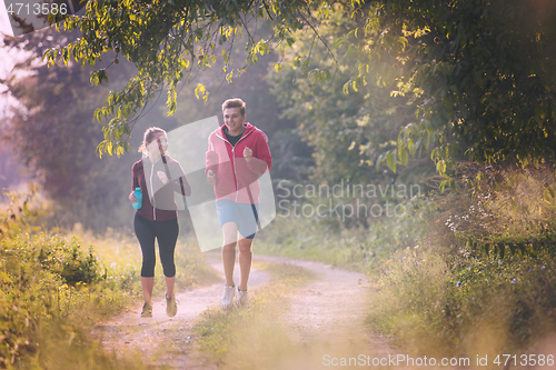 Image of young couple jogging along a country road
