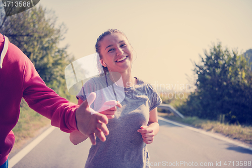 Image of young couple jogging along a country road