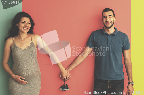 Image of young happy couple holding newborn baby shoes