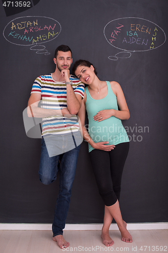 Image of pregnant couple writing on a black chalkboard