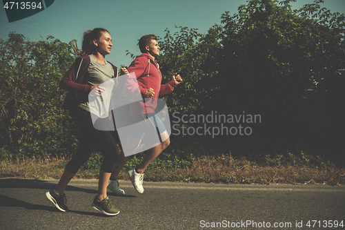 Image of young couple jogging along a country road