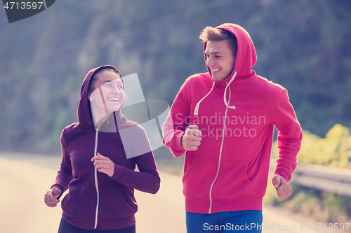 Image of young couple jogging along a country road