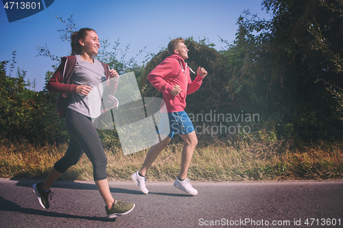 Image of young couple jogging along a country road