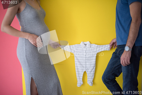 Image of young couple holding baby bodysuits