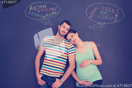 Image of pregnant couple writing on a black chalkboard