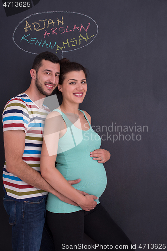 Image of pregnant couple writing on a black chalkboard