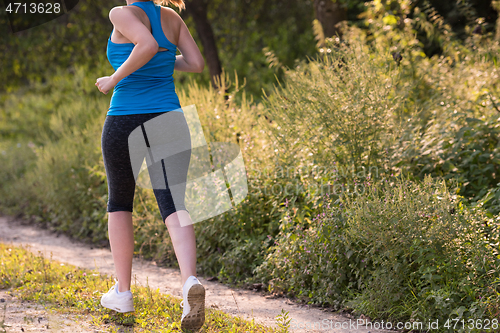 Image of woman jogging along a country road