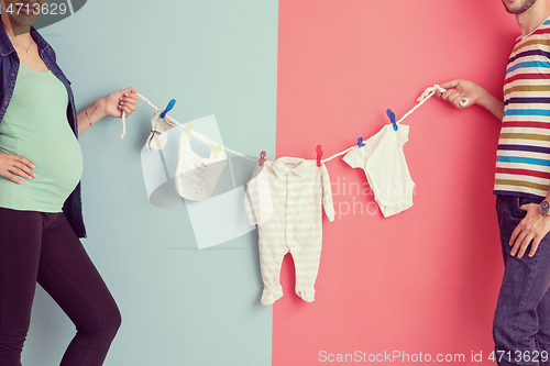 Image of young couple holding baby bodysuits