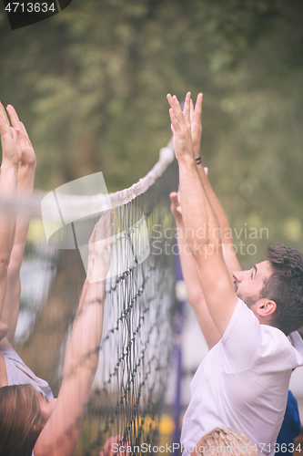 Image of group of young friends playing Beach volleyball