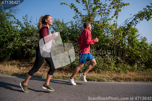 Image of young couple jogging along a country road