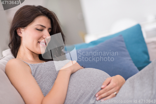 Image of pregnant woman sitting on sofa at home