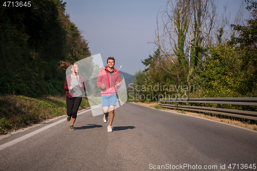 Image of young couple jogging along a country road