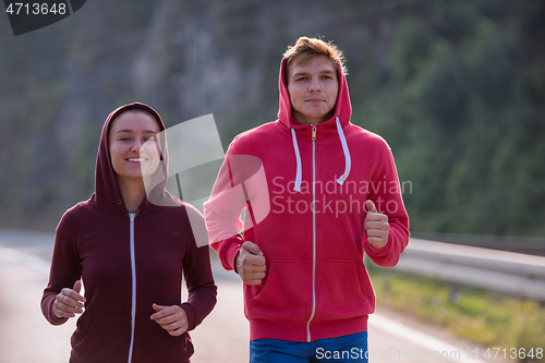 Image of young couple jogging along a country road
