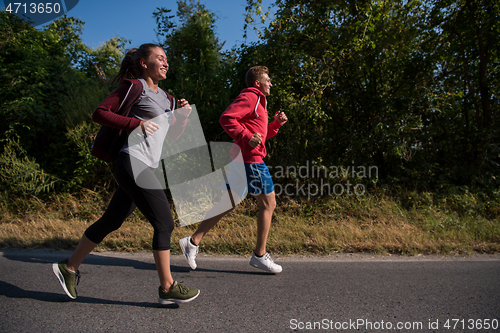 Image of young couple jogging along a country road