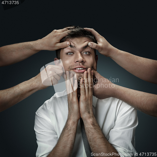 Image of A young man surrounded by hands like his own thoughts