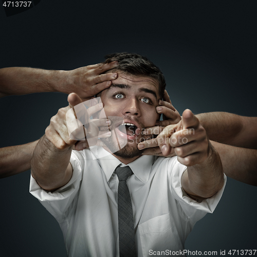 Image of A young man surrounded by hands like his own thoughts