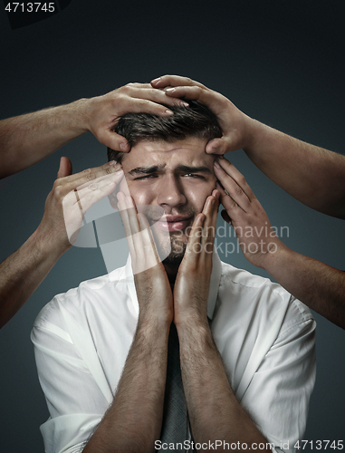 Image of A young man surrounded by hands like his own thoughts